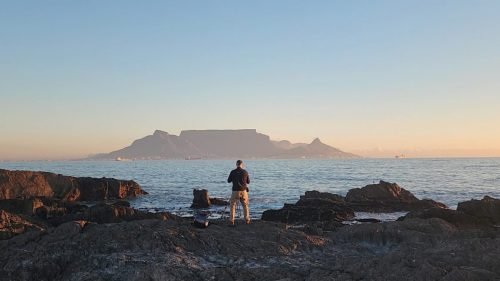 A client photographing Cape Town postcard over the ocean shot of Table Mountain. 